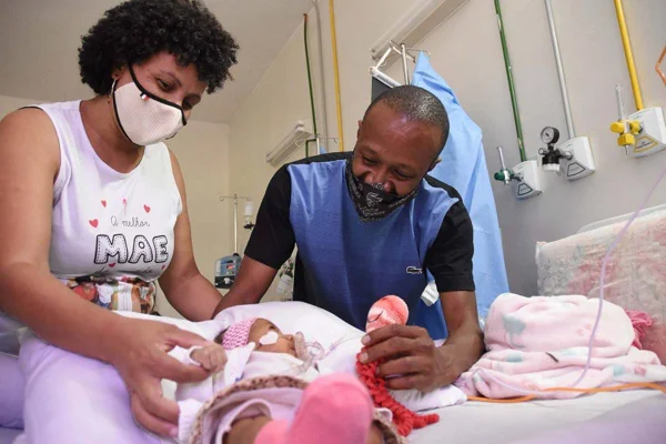 Pais brincam com bebê em quarto de hospital - Metrópoles