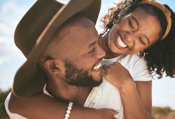 Casal negro sorrindo um para o outro e abraçando, ele de chapeu e ela com lenço na cabeça- Metrópoles