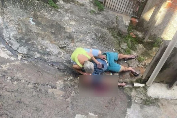 Imagem colorida de mãe chorando em cima do corpo de filho. Metrópoles