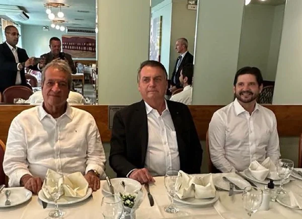 Fotografia colorida mostra Valdemar Costa Neto, Jair Bolsonaro e André do Prado sentados em uma mesa de restaurante - Metrópoles