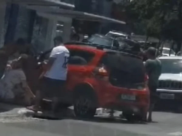 Imagem mostra veículo vermelho cercado por pessoas - Metrópoles