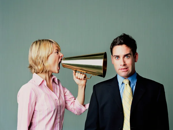 Na imagem colorida, mulher grita para homem usando um megafone - Metrópoles