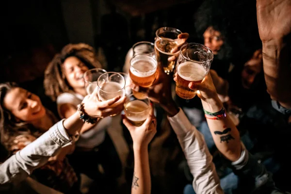 foto colorida pessoas em um bar brindando com cerveja