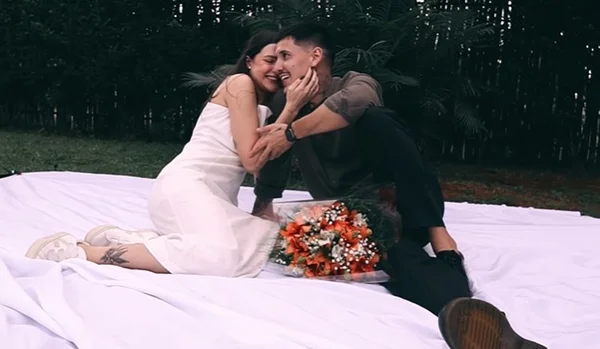 Casal sentado no chão ao lado de buquê de flores