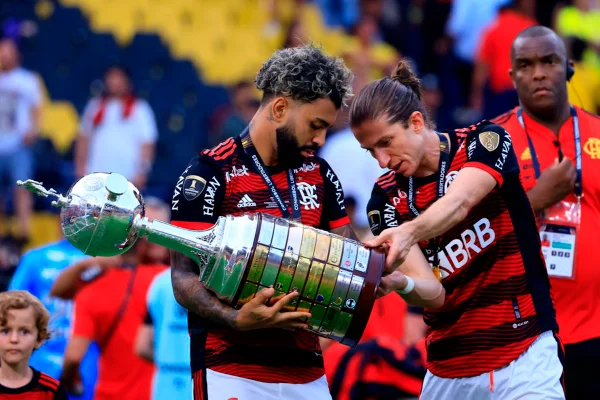 Imagem colorida de Gabigol e Filipe Luís com a taça da Libertadores - Metrópoles