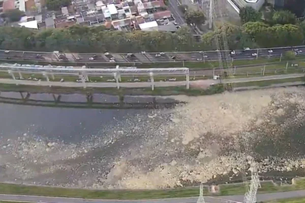Imagem colorida mostra trecho de rio visto de cima. No meio da água do rio há uma mancha de cor clara, aparentando espuma - Metrópoles