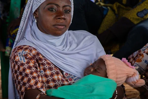 Foto colorida de mulher africana segurando um bebê - Metrópoles