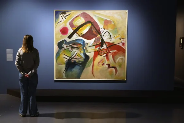 Imagem mostra mulher de costas contemplando um quadro de arte abstrata - Metrópoles