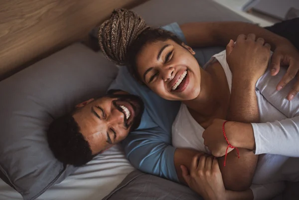 Homem e mulher deitados rindo - Metrópoles