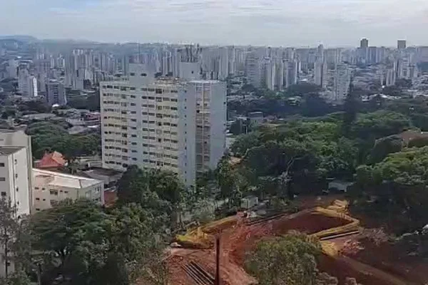 Imagem do alto mostra terreno com árvores nos cantos e terra ao meio, com uma escavadeira movendo terra