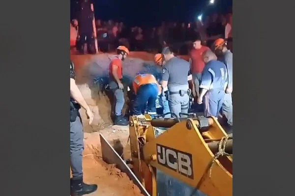 retroescavadeira cercada de bombeiros durante operação para salvar menino que caiu em buraco