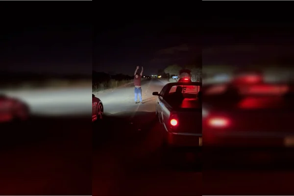 Homem balançando os braços em racha em rodovia