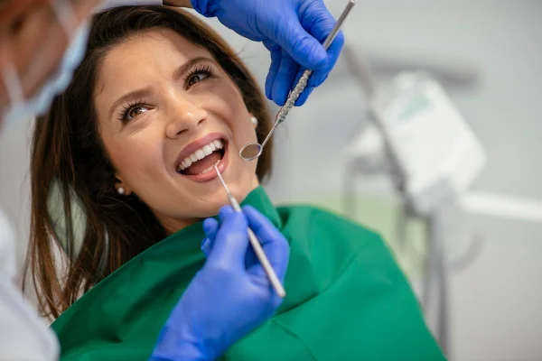 Imagem colorida de mulher sorrindo no dentista - metrópoles