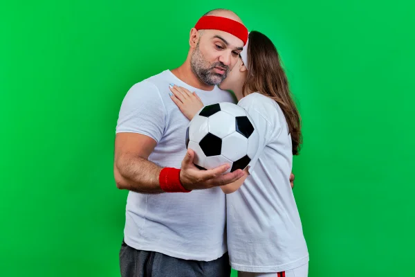 Foto colorida de jogador de futebol abraçado em mulher