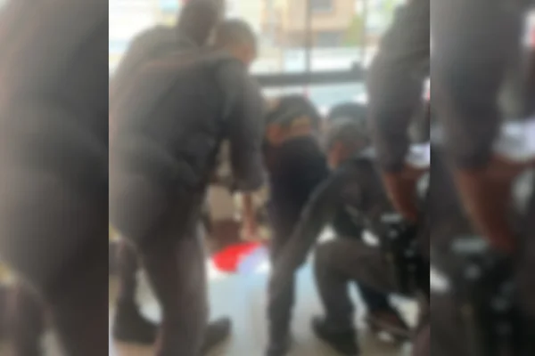 Imagem colorida de policiais tentando socorrer homem que deu tiro em si próprio dentro de delegacia - Metrópoles