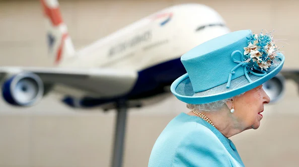 Rainha Elizabeth II em frente a imagem de avião, usando roupa e chapéu azul tiffany - Metrópoles