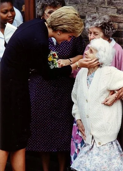 A princesa Diana acaricia o rosto de uma idosa ao visitar um asilo em Londres, no início da década de 1990 A princesa Diana acaricia o rosto de uma idosa ao visitar um asilo em Londres, no início da década de 1990