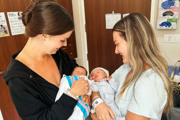 Foto colorida de duas mulheres segurando dois bebês - Metrópoles