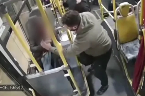 Imagem colorida mostra mulher atingida por pedra sendo socorrida por outro passageiro do ônibus. Metrópoles