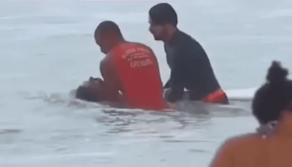 Foto colorida mostra surfista sendo resgatado por bombeiros no Rio de Janeiro - Metrópoles