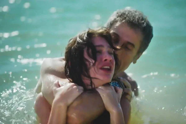 foto colorida de cena de novela com homem segurando mulher pelo pescoço no estilo mata leão dentro de rio - metrópoles