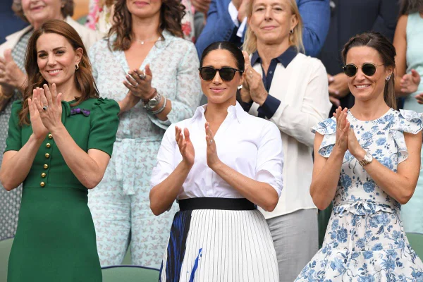 Foto colorida. Kate Middleton, Meghan Markle e Pippa Middleton em uma arquibancada