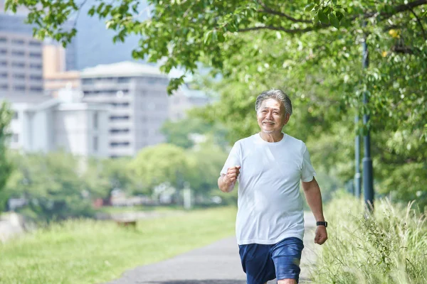 Foto colorida de homem japonês caminhando em área verde - Metrópoles