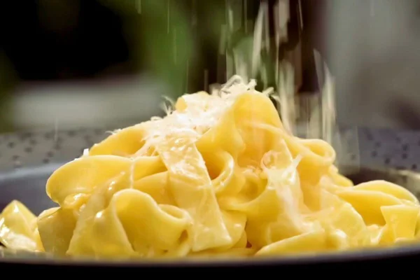 queijo sendo ralado em cima de prato de fettuccine alfredo