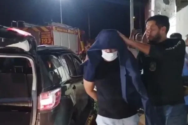 Imagem colorida de suspeito sendo conduzido por policiais