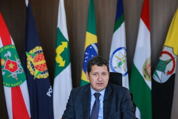 O novo secretário de segurança do Distrito Federal, Sandro Avelar, posa para foto em sua sala com bandeiras das forças de segurança do DF ao fundo. Ele fala gesticulando - Metrópoles