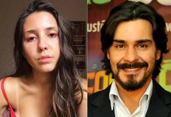 Na imagem colorida, uma menina esta à esquerda e um homem à direita. Ela tem cabelos longos castanhos, olha fixamente para a camera e usa vestido vermelho. Ele usa casaco preto, blusa branca, tem cabelos escuros, bigode e sorri para a camera