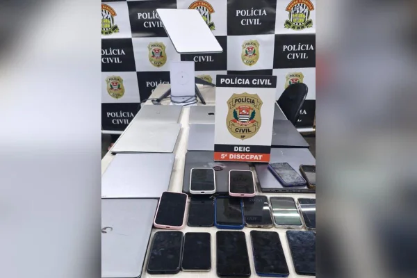 Imagem colorida de celulares e notebook apreendidos com quadrilha em cima de uma mesa - Metrópoles
