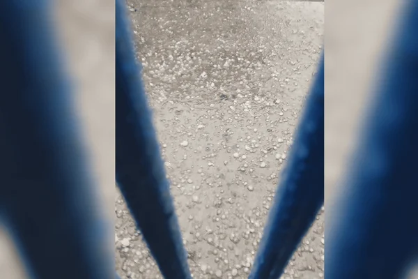Imagem colorida de uma rua com pontos de alagamentos e pedras de granizo - Metrópoles