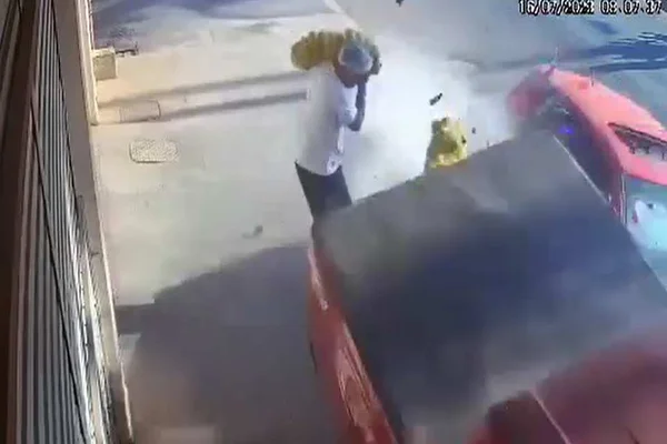 Print de vídeo. Homem com camisa branca segura saco de laranjas enquanto carro atinge caminhonete perto dele