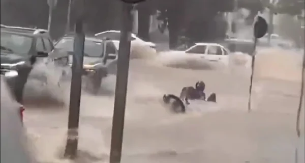 Imagem colorida de motociclista sendo arrastado pela água da chuva