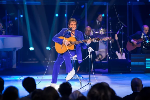 Rei Roberto Carlos cantando e tocando violão em palco