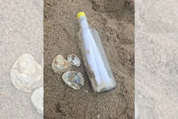 foto colorida de garrafa de vidro na praia com cinzas