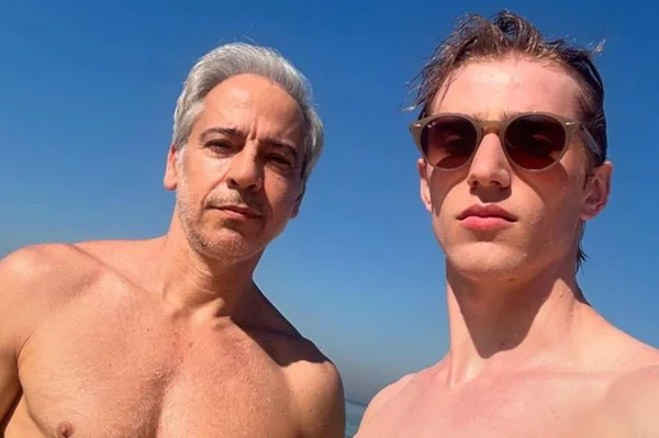 foto colorida de homem de cabelos brancos ao lado de homem jovem de oculos escuros - metrópoles