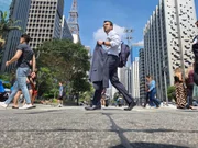 Homem caminha sob sol com paletó na mão em trecho da Avenida Paulista; SP vive onda de calor 