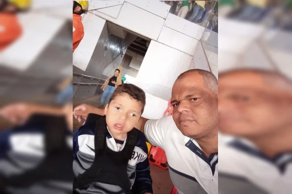 Imagem colorida de criança com condição de saúde que o colocou em uma cadeira de roda