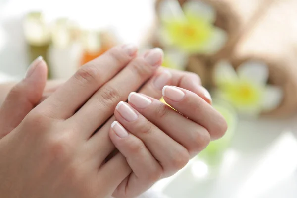 Mão feminina com unhas francesinhas brancas