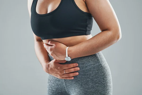 Foto colorida de mulher com a mão na barriga - Metrópoles