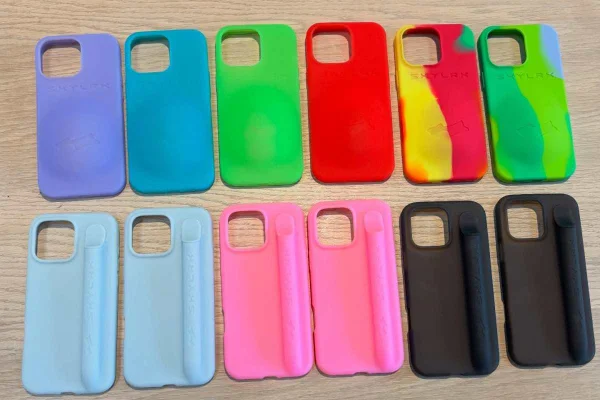 A imagem mostra diversas capinhas de celulares dispostas sob uma mesa