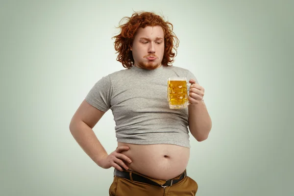 Homem com "Barriga de chopp", segurando um chopp- Metrópoles