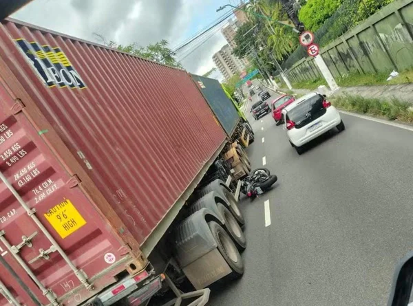 moto tombada debaixo de carreta