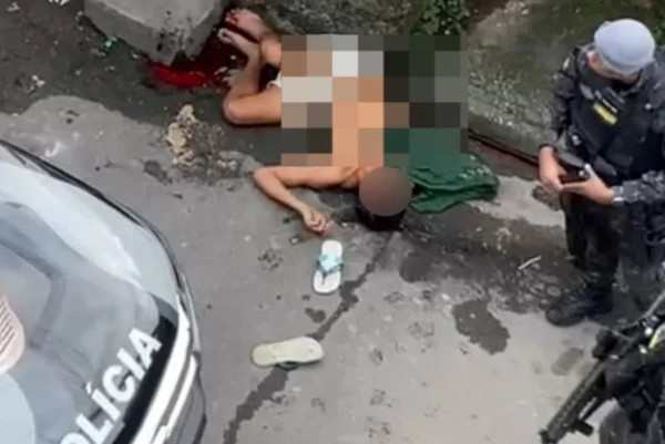 Imagem mostra policial militar (PM) ao lado de homem baleado - Metrópoles