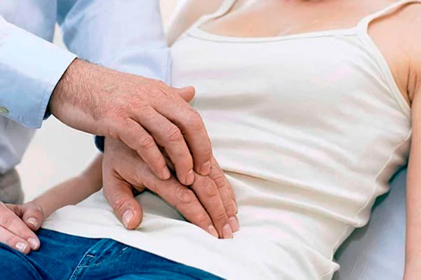 Imagme colorida de mulher sentada enquanto homem pressioan sua barriga - Metrópoles