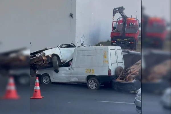 Imagem colorida de quatro carros colididos, com dois cones à frente
