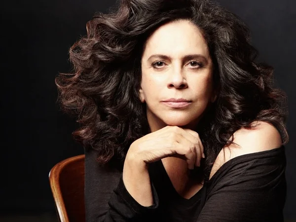 Gal Costa posa sentada vestida de preto - Metrópoles