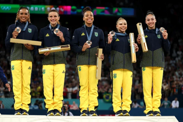 Imagem colorida das ginastas brasileiras no pódio, com medalha de bronze inédita- Metrópoles